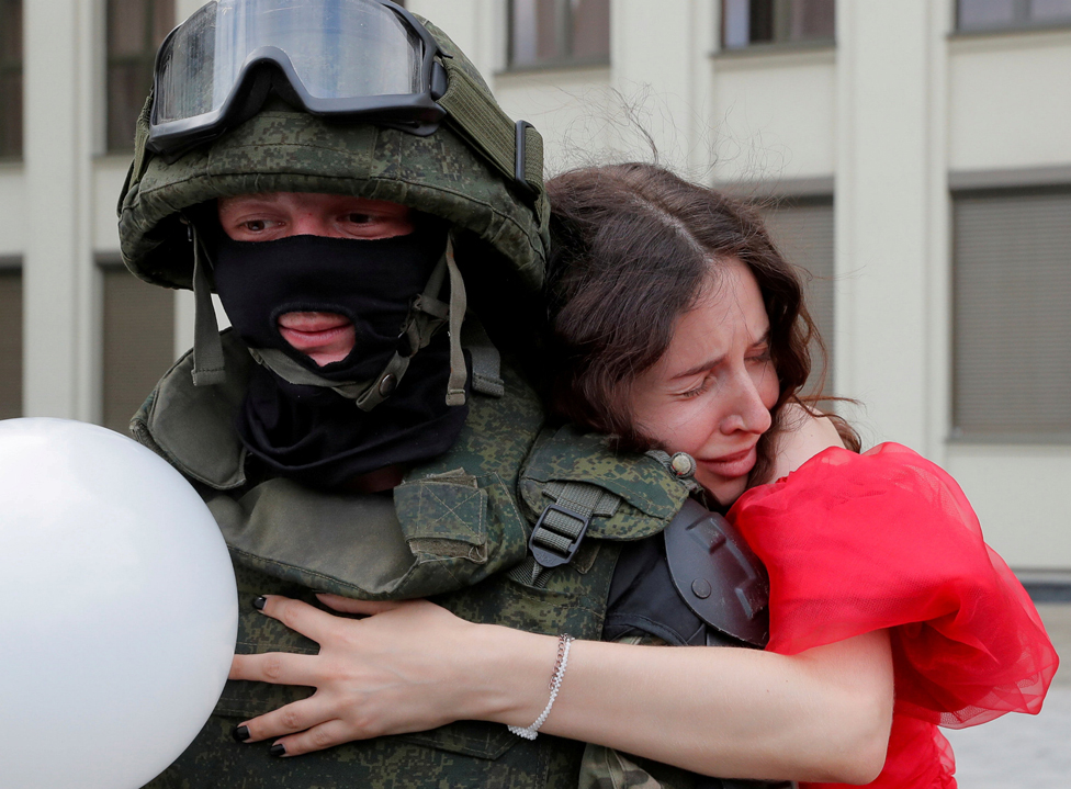 A woman embraces a member of the Belarusian interior troop near the Government House in Independence Square in Minsk, Belarus, 14 August 2020