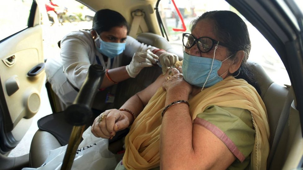 A woman receives a dose of Covid-19 vaccine at a drive-thru vaccination site in Noida, India, May 2021