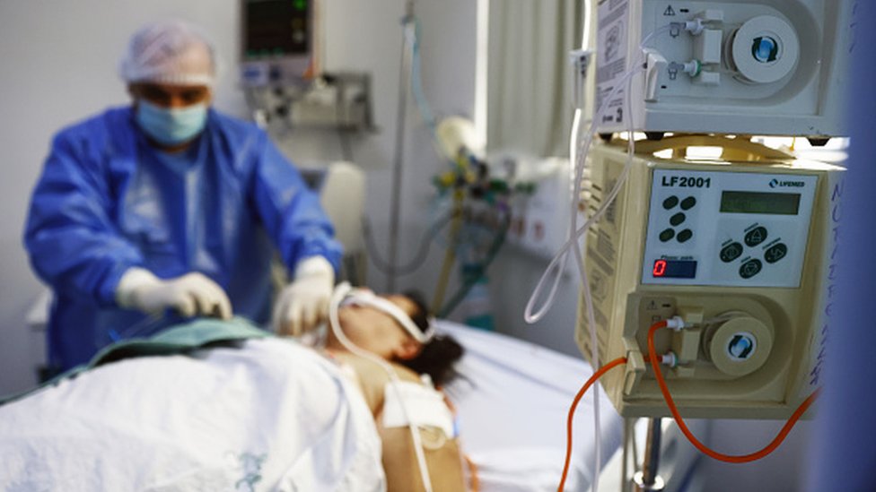 Health professional assists patient in ICU